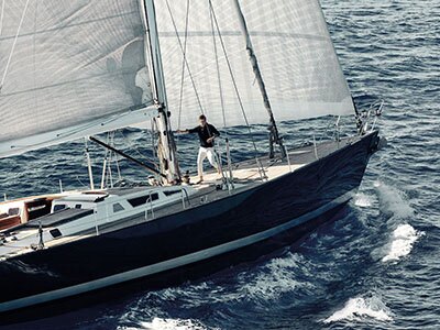 The yacht under full sail, in the middle distance, with Eddie Redmayne holding onto to the central mast. 